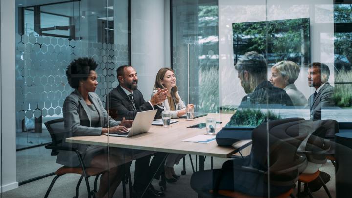 Small team collaborating around a meeting table to discuss business strategy and technology initiatives.