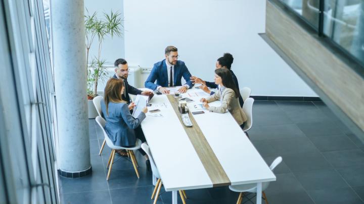 Team meeting in a modern office with professionals discussing documents around a conference table
