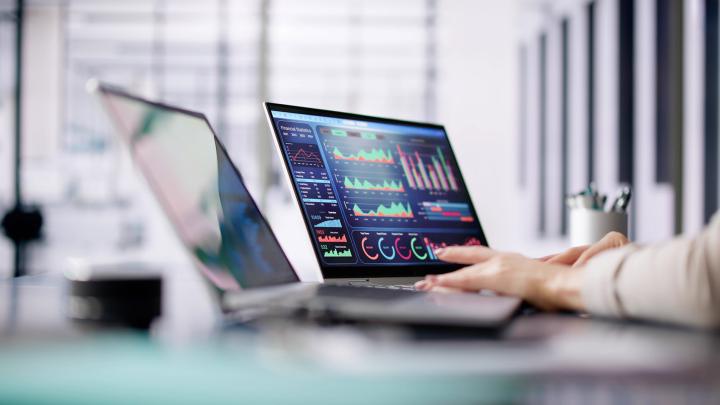 Critical application performance dashboard displayed on a laptop screen, showing real-time analytics, charts and operational metrics in a modern office environment.