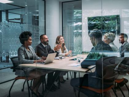 Small team collaborating around a meeting table to discuss business strategy and technology initiatives.