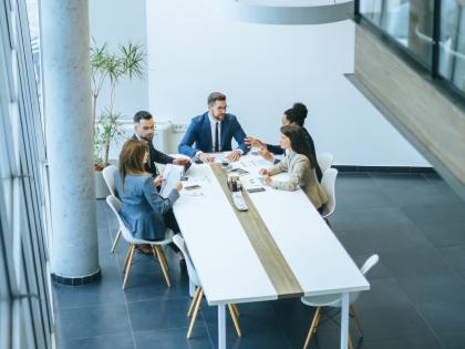 Team meeting in a modern office with professionals discussing documents around a conference table